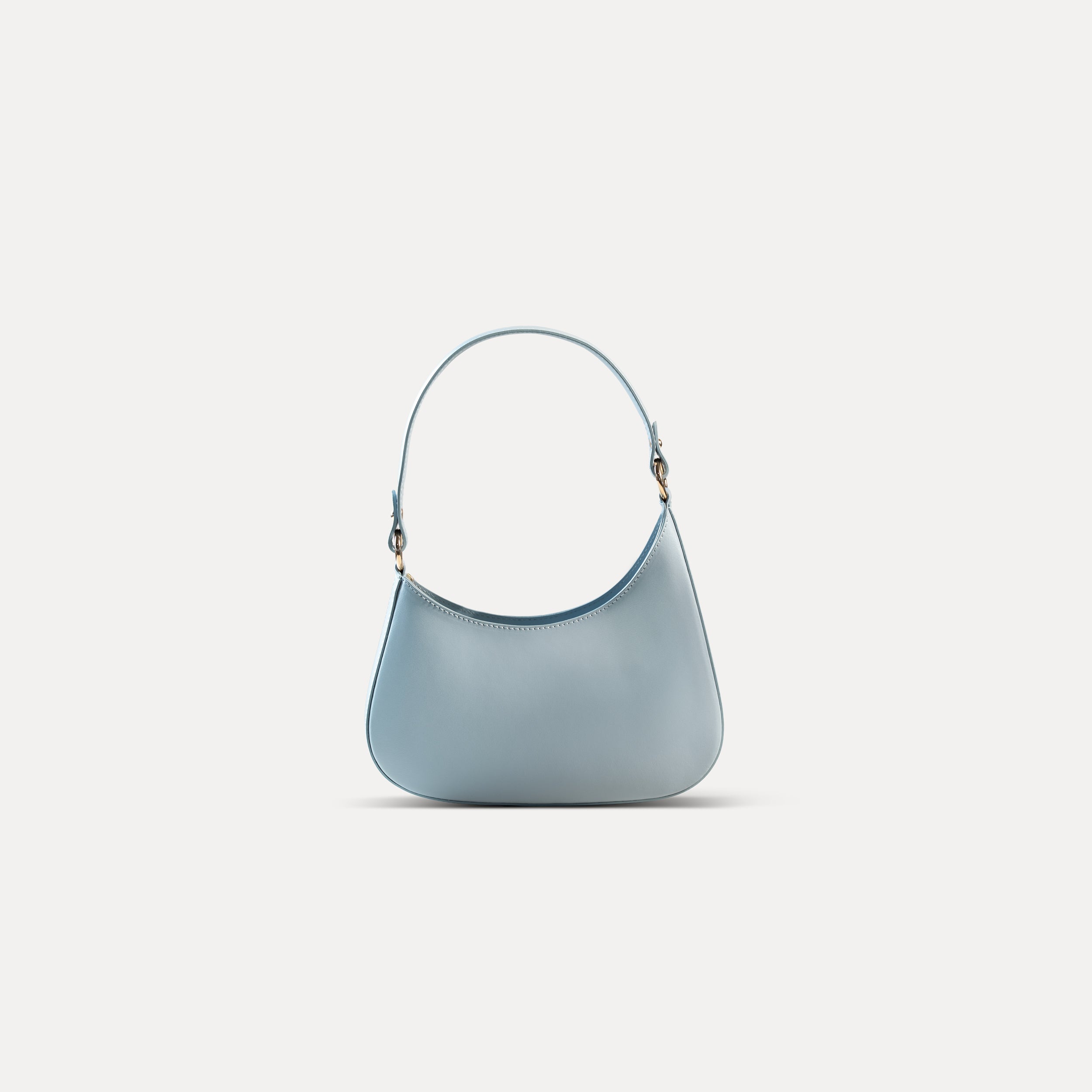 sac à main forme hobo demi lune asymétrique pour femme en cuir lisse bleu pâle avec bandoulière sur fond blanc