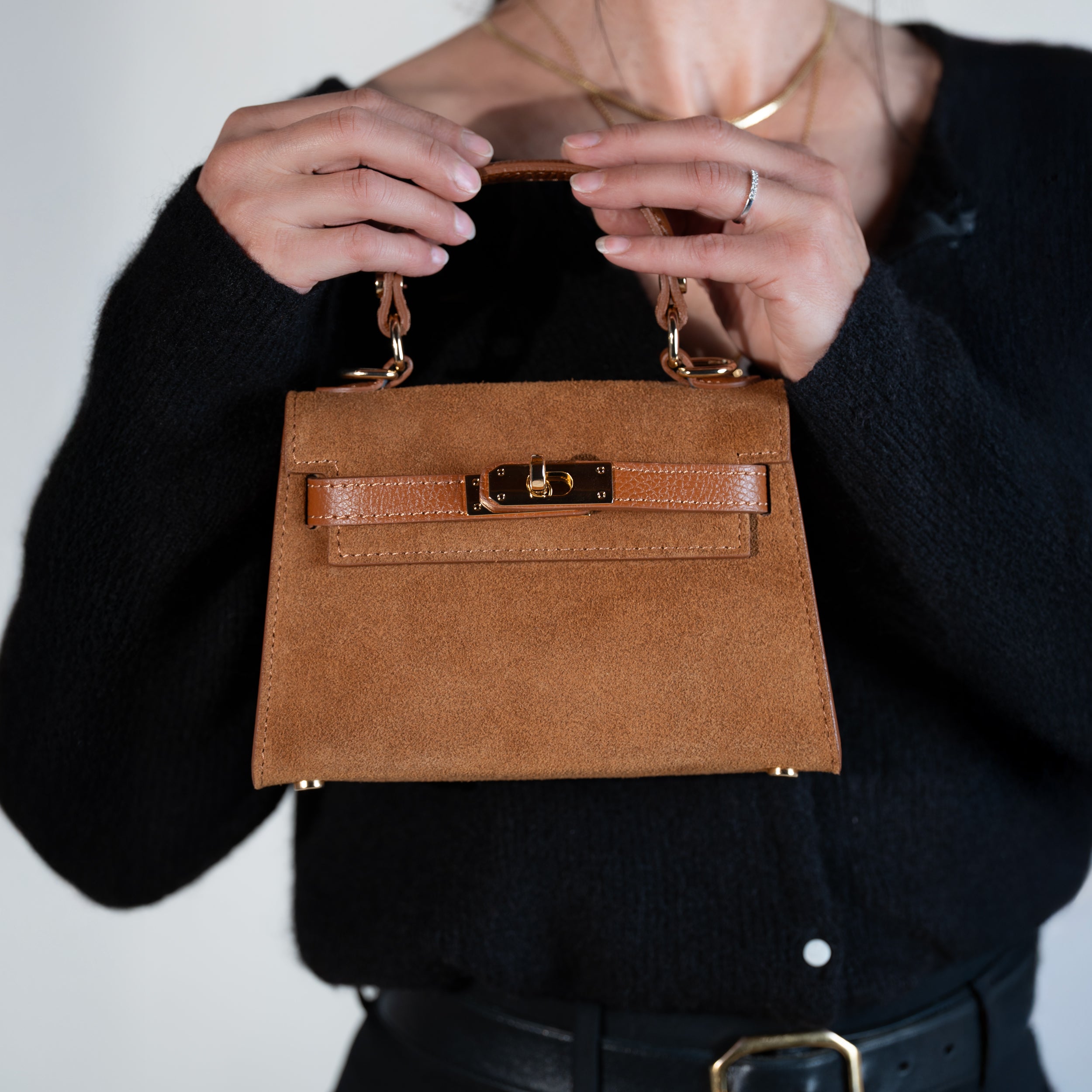 sac à main femme en daim top handle fermé avec fermoir tourniquet et bijouterie doré dans un cuir suédé camel porté à la main