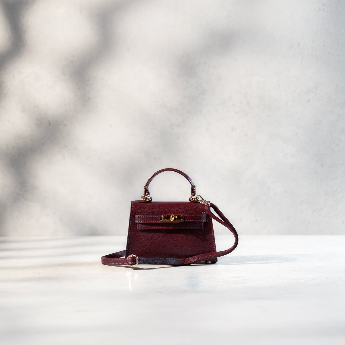 sac à main femme en cuir saffiano bordeaux top handle avec fermoir tourniquet et bijouterie doré avec bandoulière