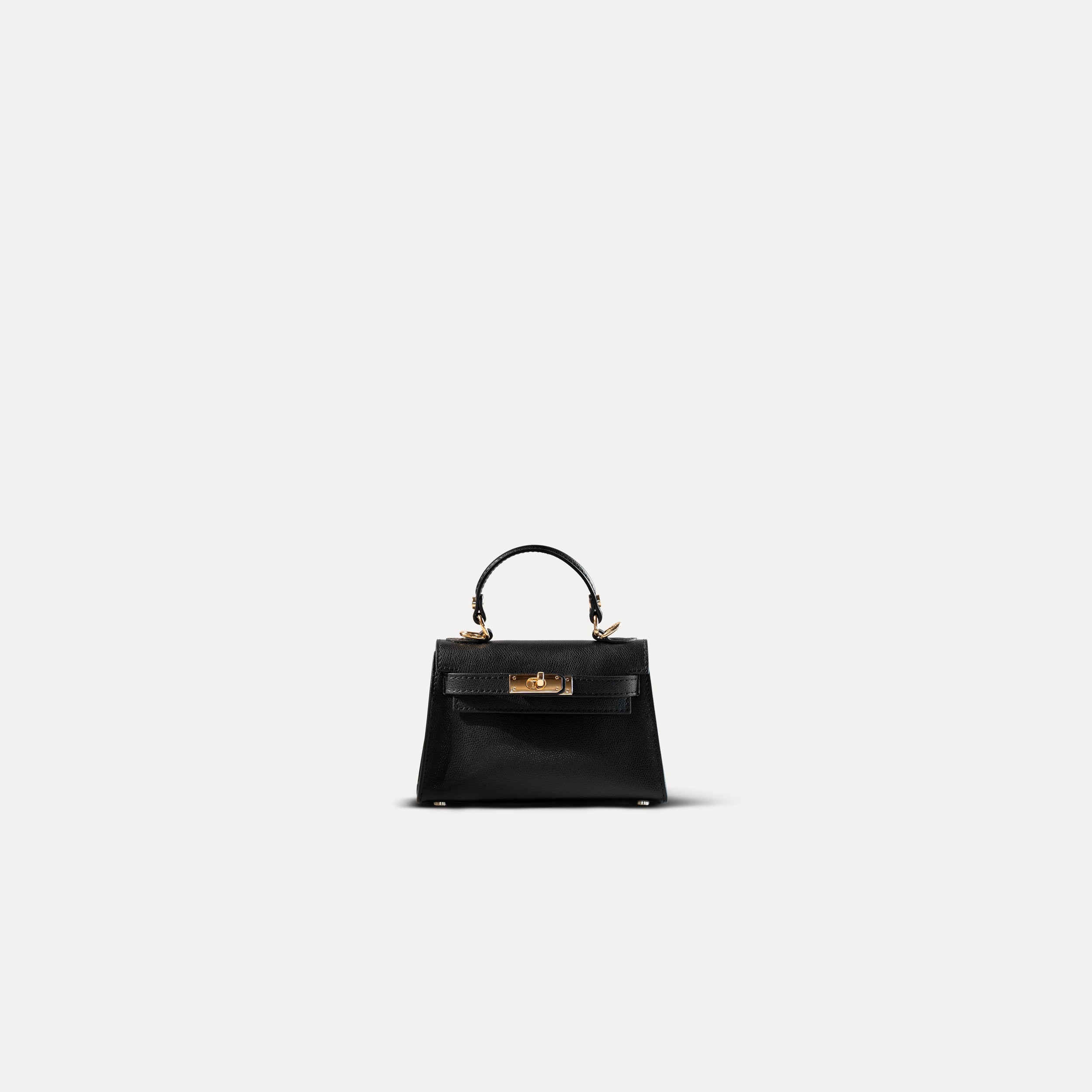 sac à main forme top handle chic pour femme en cuir saffiano noir avec bandoulière et bijouterie dorée sur fond blanc